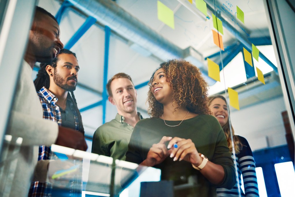 Equipo de trabajo pega post its en cristal de oficina