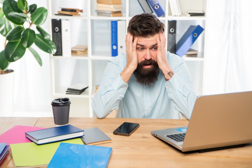 Hombre en oficina frustrado frente a computadora